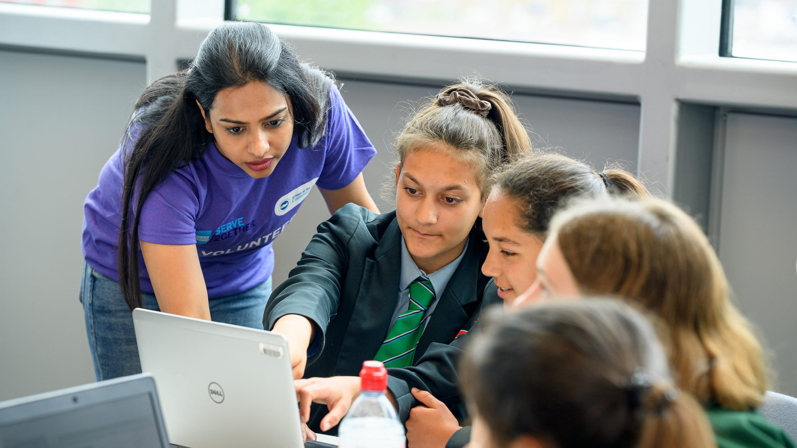 girls learning with AMEX volunteer