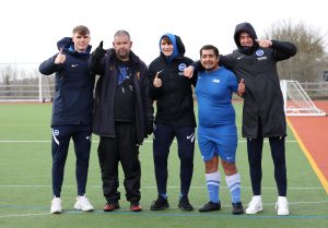 Albion academy scholars Leigh Kavanagh, Zak Emmerson and Ben Jackson standing in a group with a disability football participant during the Albion in the Community Disability Football Camp at the University of Sussex in Falmer.